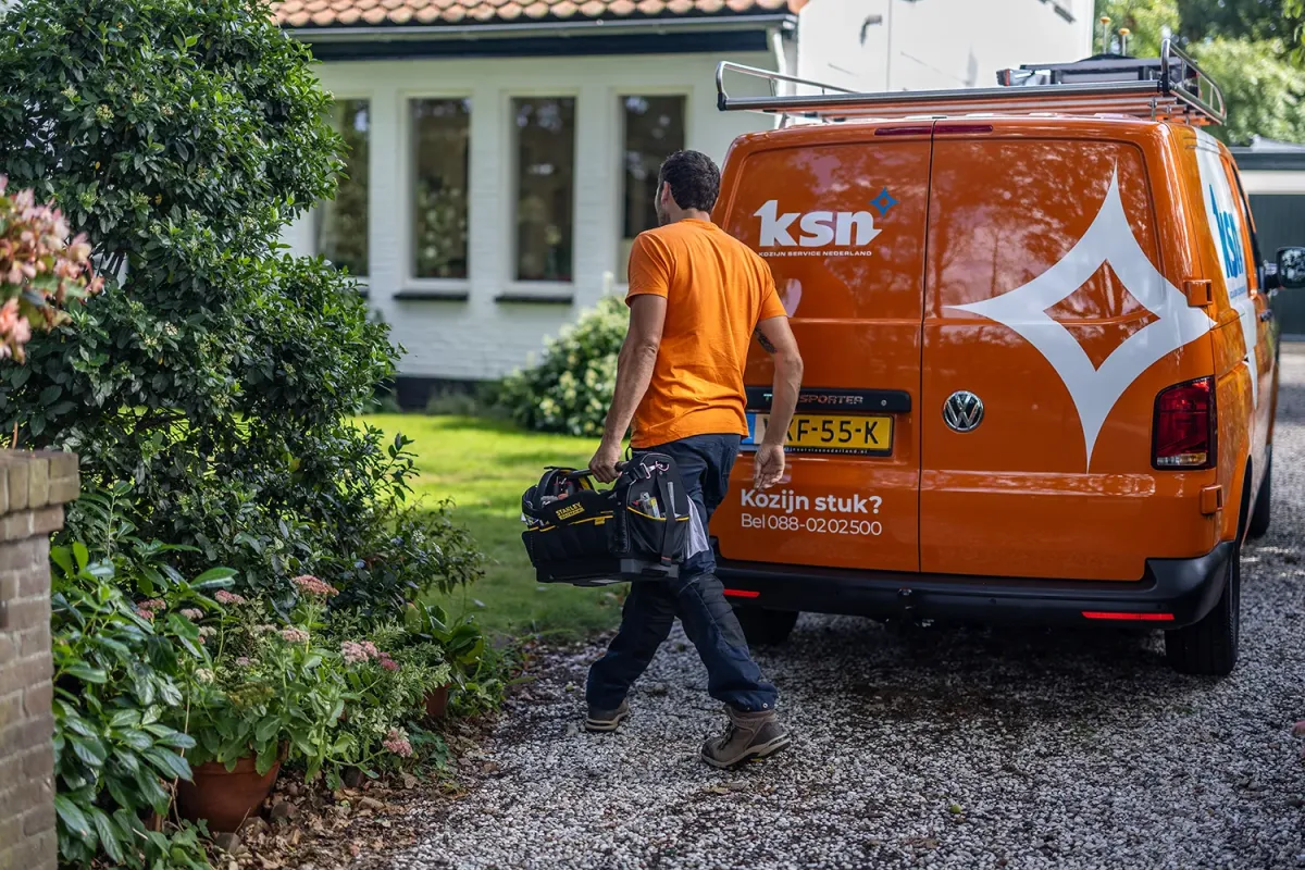 Servicemonteur met uitgeruste oranje KSN bus bij woning